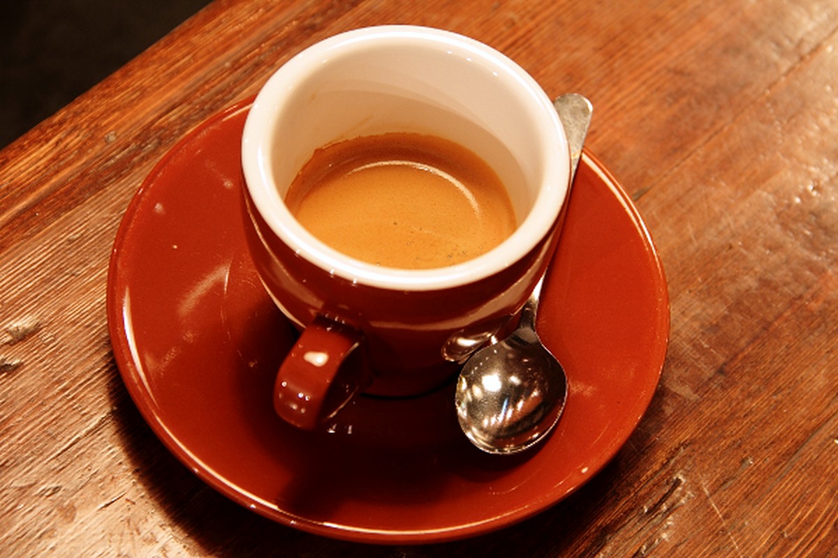 A cup of coffee and spoon on a wooden table